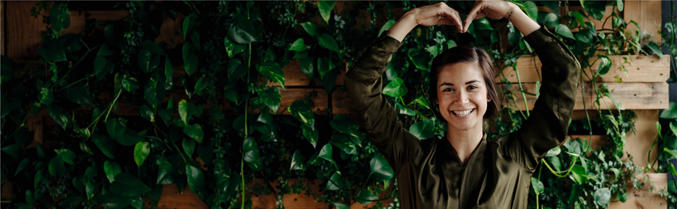 Woman standing near plants that are healthy and thriving, symbolising growth. Tips for growing a sustainable business