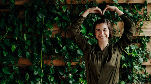 Woman standing near plants that are healthy and thriving, symbolising growth. Tips for growing a sustainable business